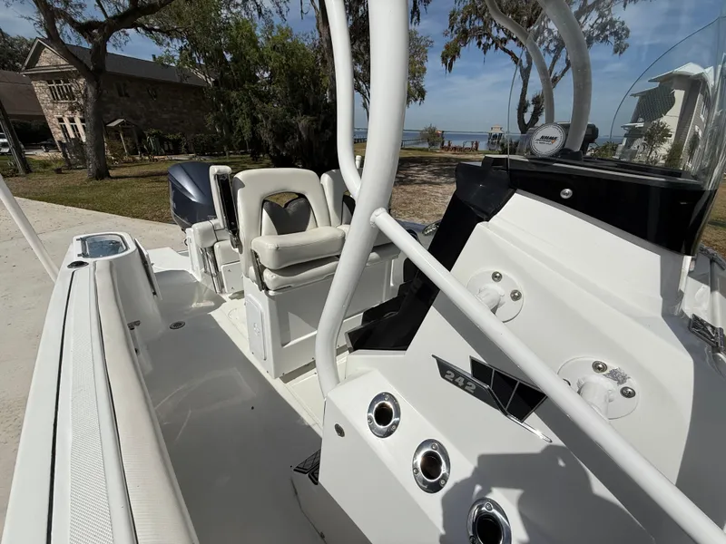 Slide: The Image of 2021 Wellcraft 242 Offshore boat interior with seating and control panel, docked near a scenic waterfront. - 46
