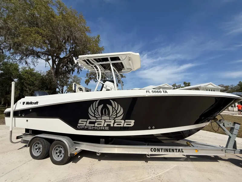 Slide: The Image of 2021 Wellcraft 242 Offshore boat on trailer, black and white design, clear sky background. - 7
