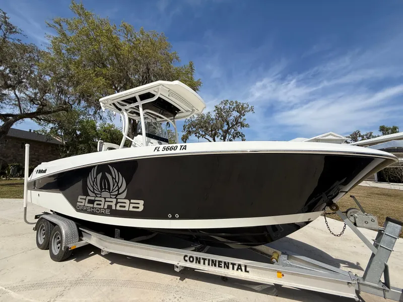 Slide: The Image of 2021 Wellcraft 242 Offshore boat on trailer, black and white design, parked outdoors. - 8