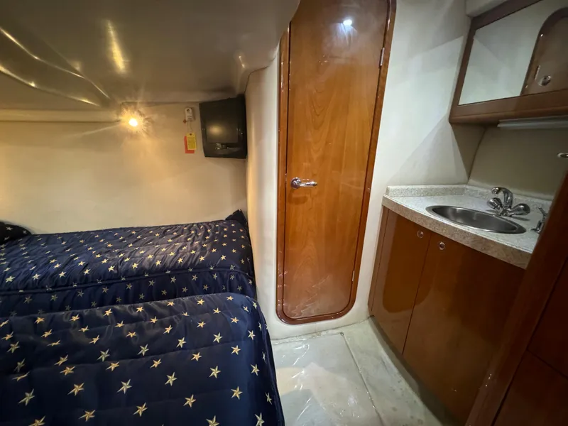 Slide: The Image of 2008 Regal Commodore 4460 cabin with twin beds, wooden door, and compact sink area. - 13