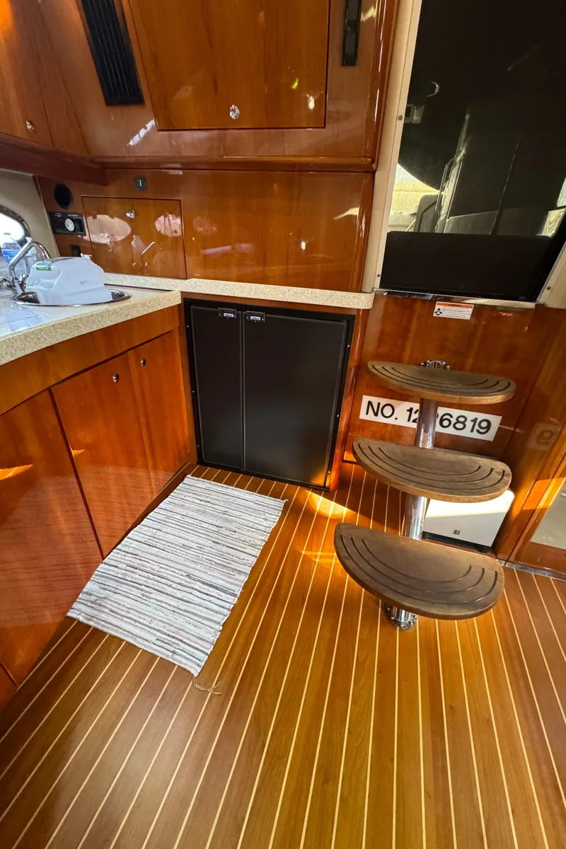 Slide: The Image of Interior of 2008 Regal Commodore 4460 yacht with wooden flooring and compact kitchen area. - 17