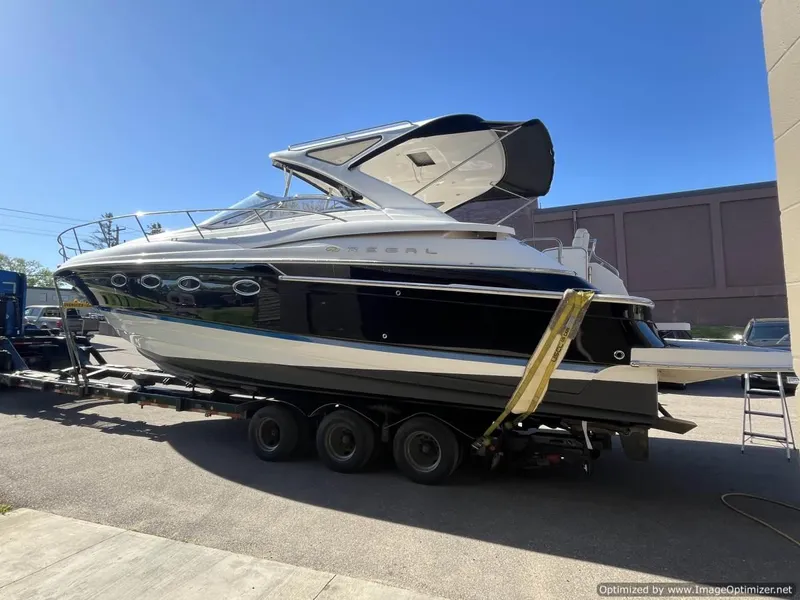 Slide: The Image of 2008 Regal Commodore 4460 yacht on trailer, parked outdoors under clear blue sky. - 27