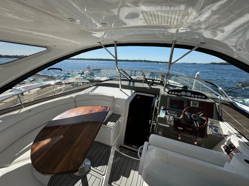 Slide: The Image of 2008 Regal Commodore 4460 yacht interior with helm, wooden table, and scenic water view. - 7
