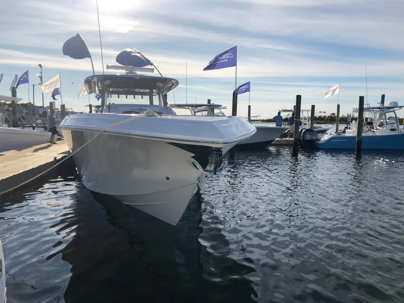 Slide: The Image of 2020 Fountain 43 NX boat docked at marina with flags and calm water. - 1