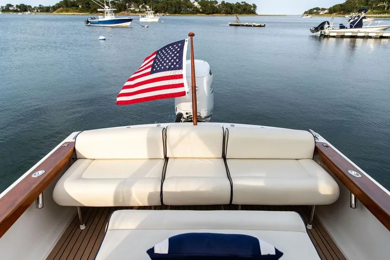 Slide: The Image of 2021 Hunt Yachts Harrier 26 with American flag, docked in serene waters. - 39