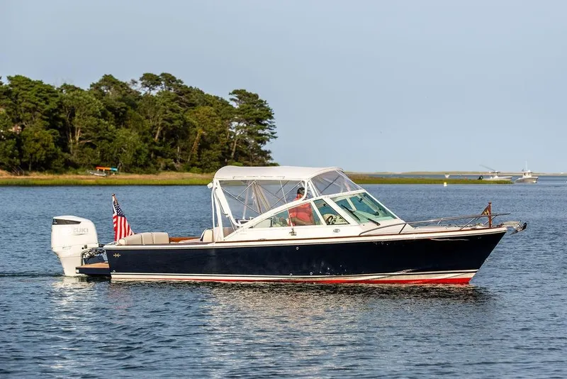 Slide: The Image of 2021 Hunt Yachts Harrier 26 cruising on a serene lake with lush green shoreline. - 48