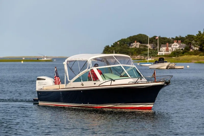 Slide: The Image of 2021 Hunt Yachts Harrier 26 cruising on a serene waterway with scenic background. - 50