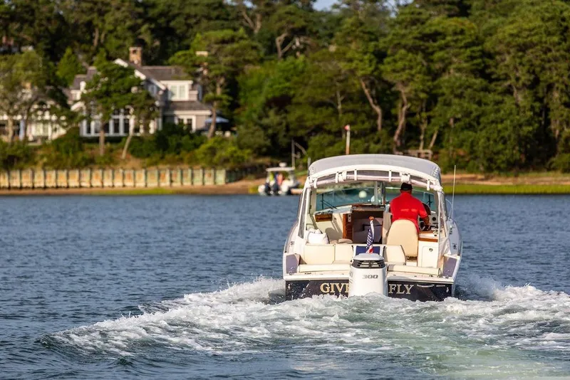 Slide: The Image of 2021 Hunt Yachts Harrier 26 cruising on a scenic lake with lush greenery. - 61
