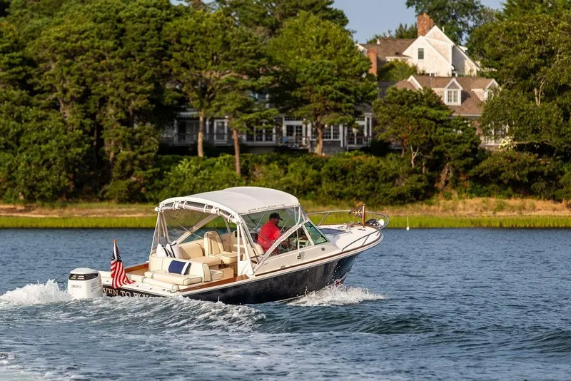 Slide: The Image of 2021 Hunt Yachts Harrier 26 cruising on a scenic lake with lush greenery. - 62