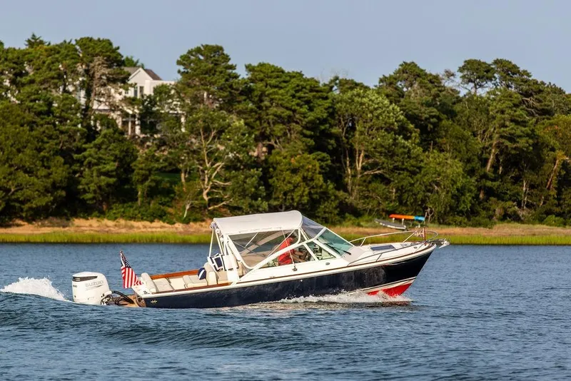 Slide: The Image of 2021 Hunt Yachts Harrier 26 cruising on a scenic lake with lush greenery. - 64