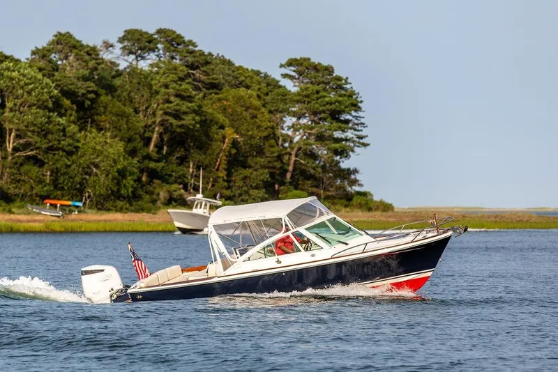 Slide: The Image of 2021 Hunt Yachts Harrier 26 cruising on a scenic lake with lush greenery. - 65