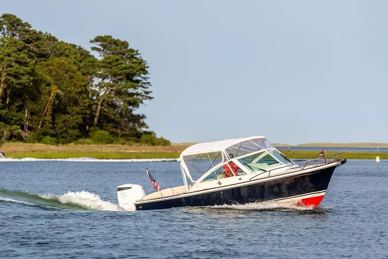 Slide: The Image of 2021 Hunt Yachts Harrier 26 cruising on a serene lake near lush greenery. - 66