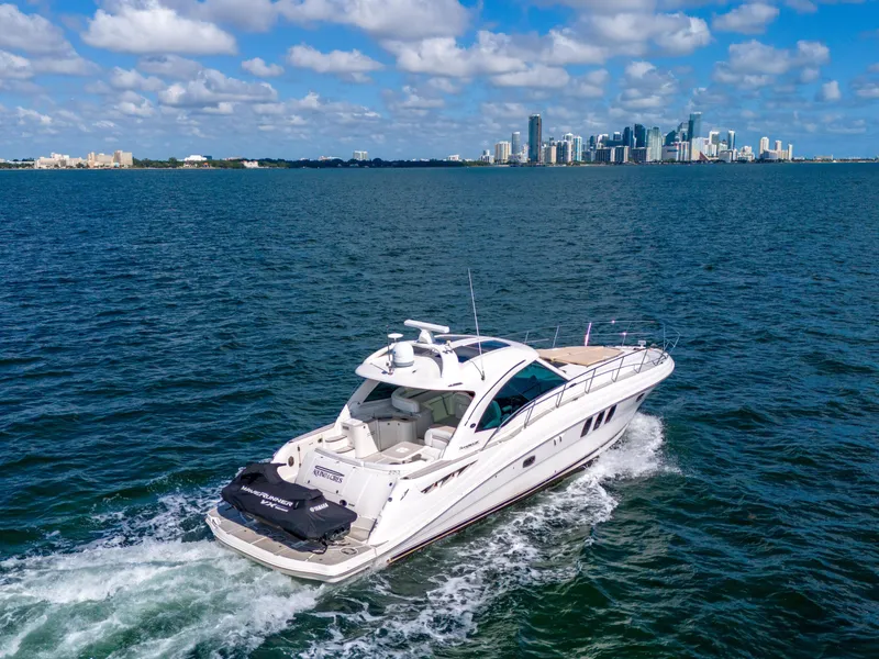 Slide: The Image of 2010 Sea Ray 500 Sundancer cruising on open water with city skyline in background. - 21