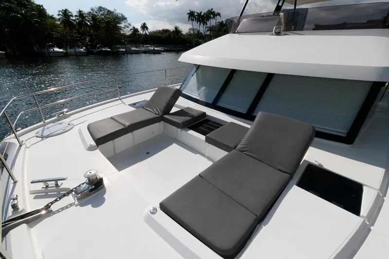 Slide: The Image of 2022 Fountaine Pajot MY6 yacht with sun loungers on deck, docked by a scenic waterfront. - 14