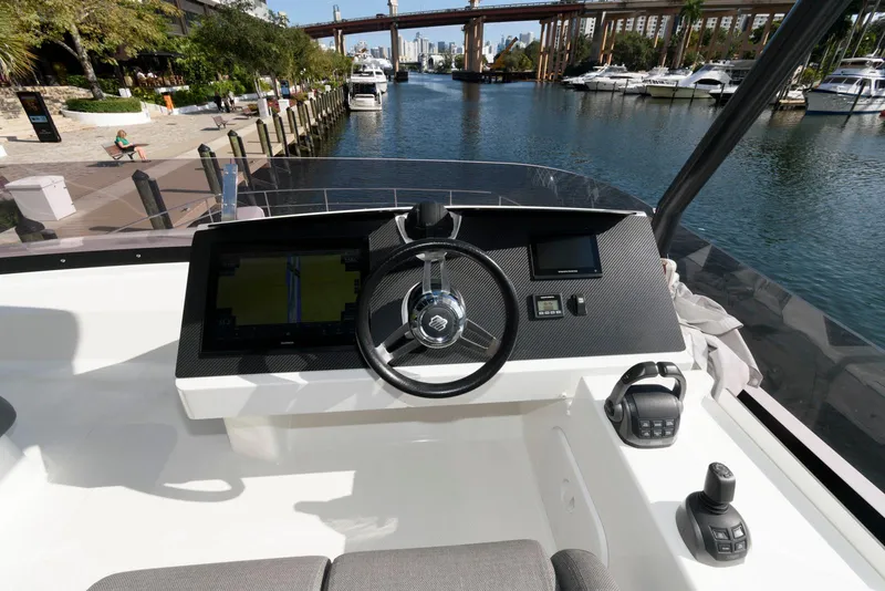 Slide: The Image of 2022 Fountaine Pajot MY6 yacht helm with modern controls, docked by a scenic waterfront. - 22