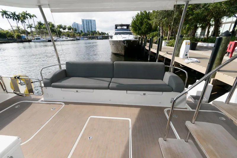 Slide: The Image of Fountaine Pajot MY6 2022 yacht deck with seating, docked by a scenic waterfront. - 9
