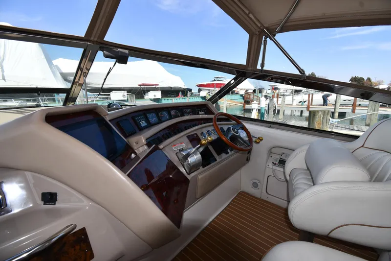 Slide: The Image of 1998 Sea Ray 500 Sundancer helm with luxurious seating and advanced controls, docked at marina. - 15