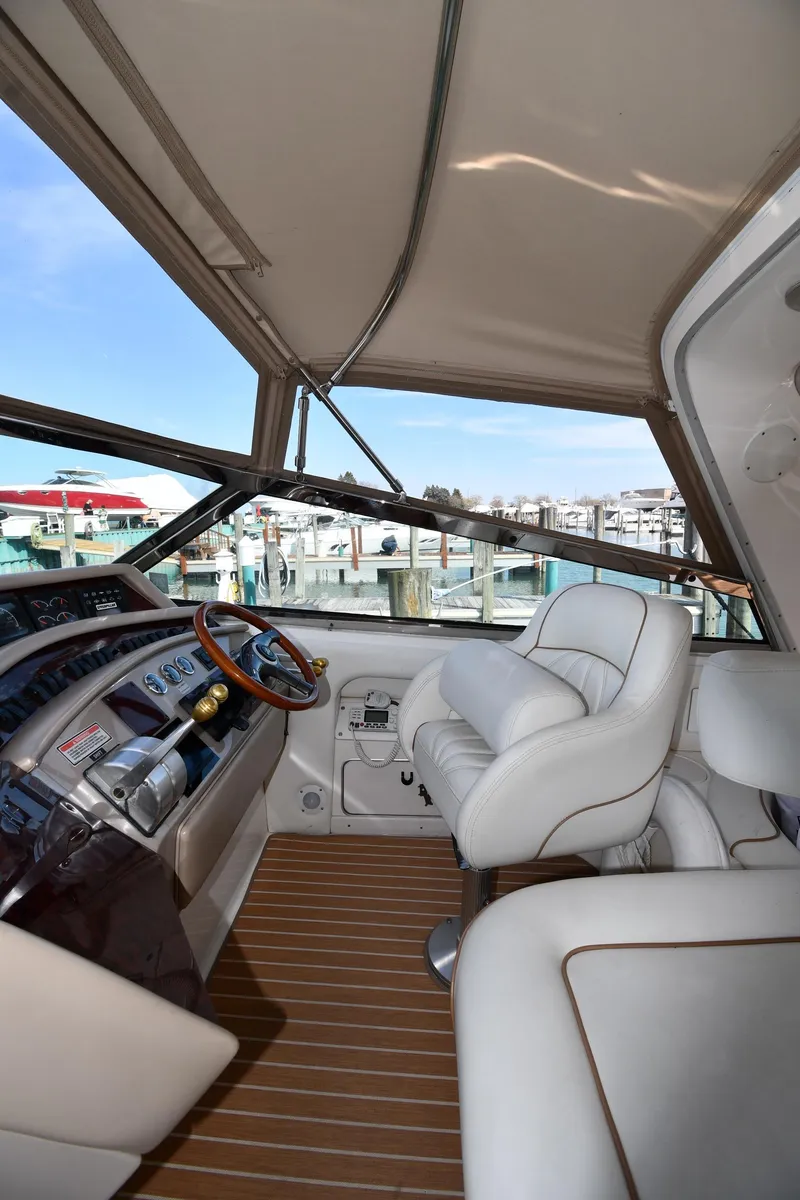 Slide: The Image of 1998 Sea Ray 500 Sundancer helm with white seating and wooden flooring. - 18