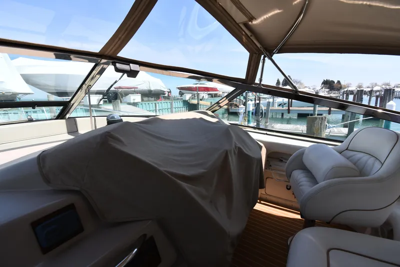 Slide: The Image of 1998 Sea Ray 500 Sundancer cockpit with covered controls and plush seating at marina. - 5