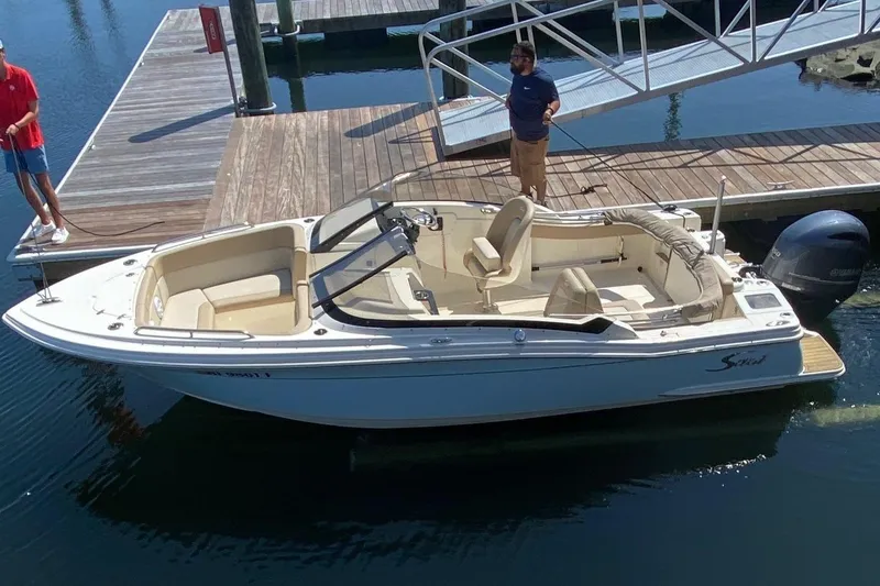 Slide: The Image of 2022 Scout 215 Dorado boat docked at marina with two people onboard. - 0