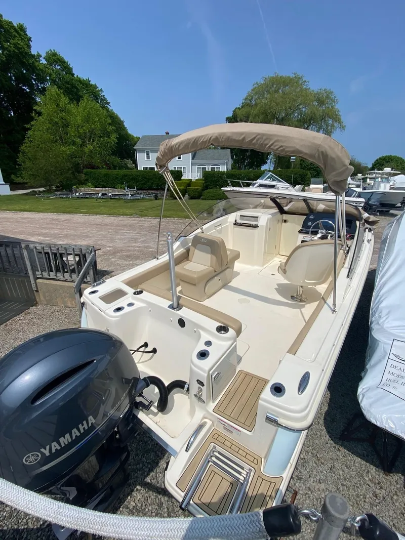Slide: The Image of 2022 Scout 215 Dorado boat with Yamaha engine, beige interior, and canopy, parked outdoors. - 14