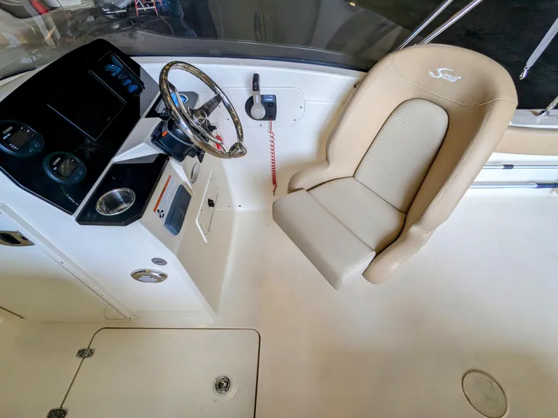 Slide: The Image of 2022 Scout 215 Dorado boat interior with steering wheel and beige captain's chair. - 4