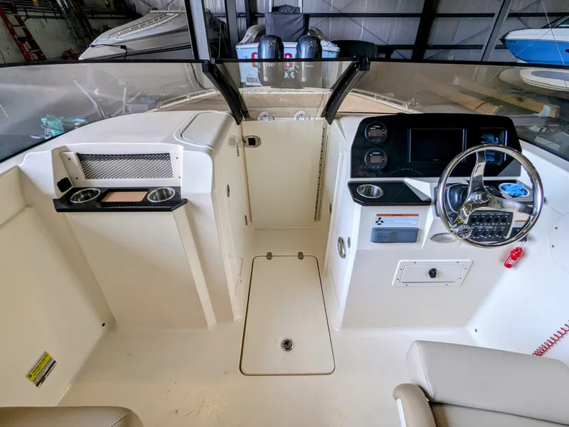 Slide: The Image of 2022 Scout 215 Dorado boat interior with steering wheel and dashboard in a storage facility. - 5