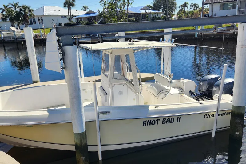 Slide: The Image of 2007 Clearwater 23cc boat named "Knot Bad II" docked in a serene marina. - 0