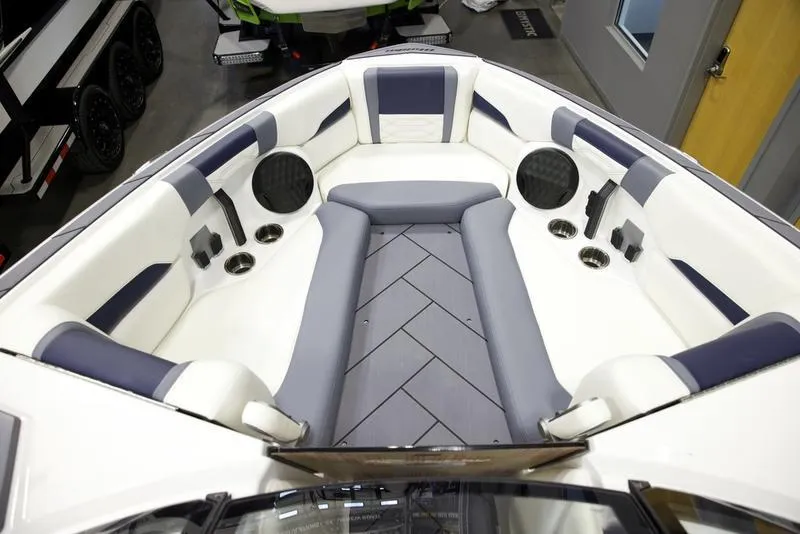 Slide: The Image of 2025 Malibu 26 LSV boat interior with gray and white seating, cup holders, and speakers. - 17
