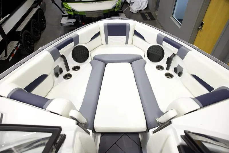 Slide: The Image of 2025 Malibu 26 LSV boat interior with white and blue seating, speakers, and cup holders. - 20
