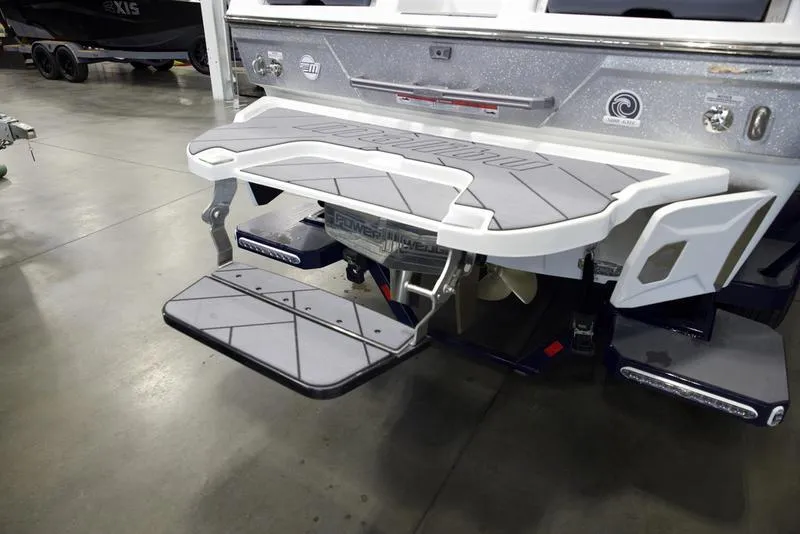 Slide: The Image of 2025 Malibu 26 LSV boat with swim platform and step ladder in a showroom. - 4