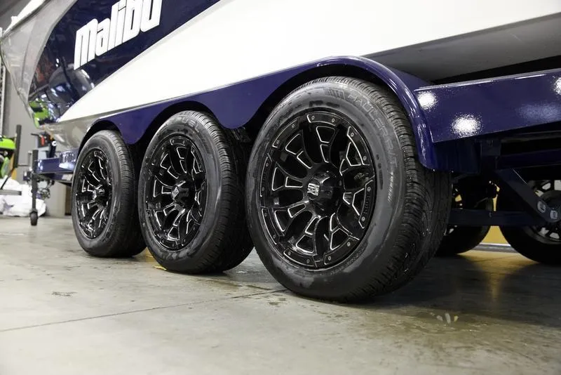 Slide: The Image of 2025 Malibu 26 LSV boat trailer with black alloy wheels in a garage setting. - 6