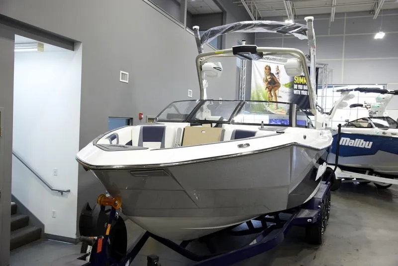 Slide: The Image of 2025 Malibu 26 LSV boat displayed indoors on a trailer. - 8