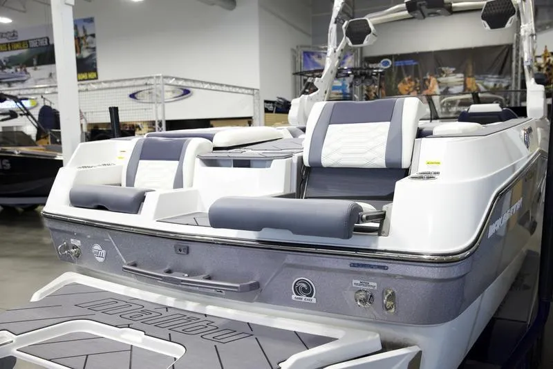 Slide: The Image of 2025 Malibu 26 LSV boat interior with modern seating and sleek design in showroom. - 9