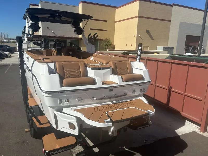 Slide: The Image of 2025 Malibu 26 LSV boat with tan seating, parked outdoors. - 8
