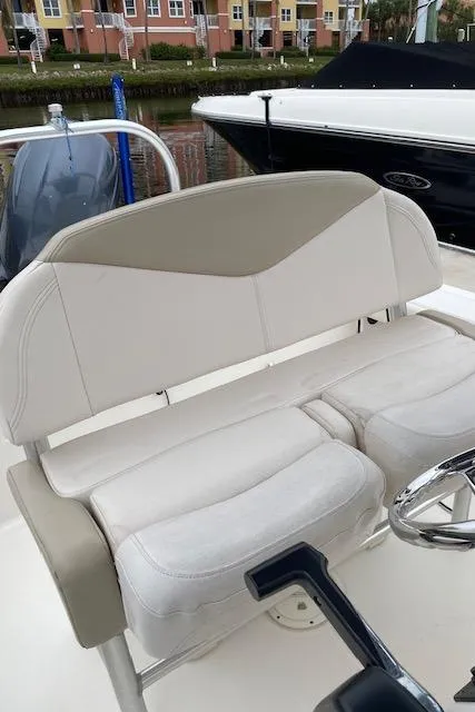 Slide: The Image of 2016 Robalo 226 Cayman boat seating with steering wheel, docked near waterfront buildings. - 13