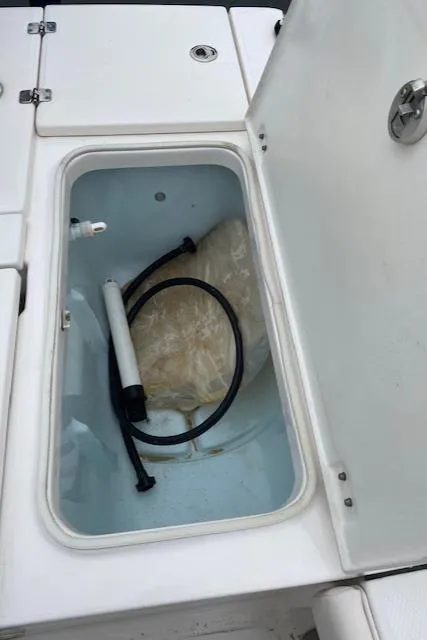 Slide: The Image of 2016 Robalo 226 Cayman storage compartment with pump and hose. - 15