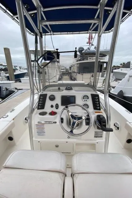 Slide: The Image of 2016 Robalo 226 Cayman boat cockpit with steering wheel and controls, docked at marina. - 16