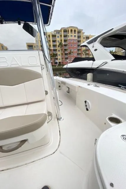 Slide: The Image of 2016 Robalo 226 Cayman boat interior, featuring seating and sleek design in a marina setting. - 21
