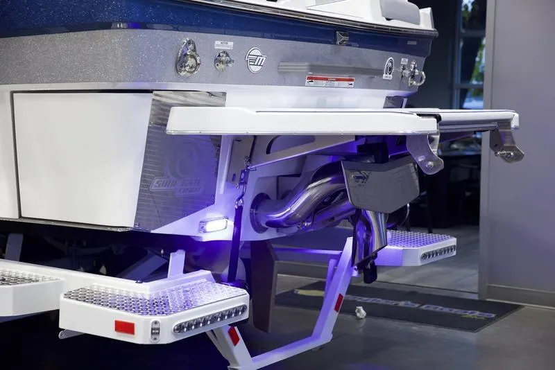 Slide: The Image of 2025 Malibu M242 boat rear view with illuminated swim platform and exhaust system. - 5