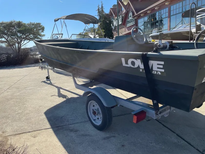 Slide: The Image of 2021 Lowe 1648 Jon boat on trailer, parked outdoors in sunny weather. - 2