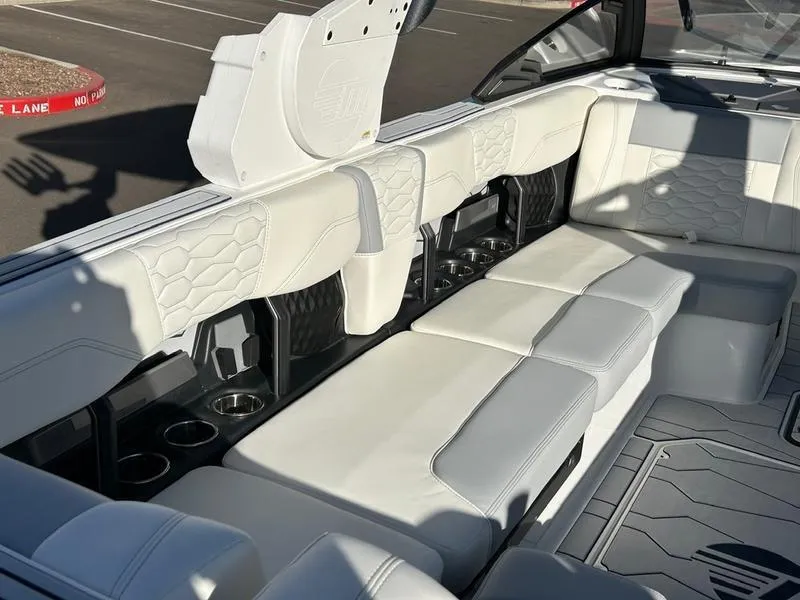Slide: The Image of 2025 Malibu 24 MXZ boat interior with white leather seating and cup holders. - 11