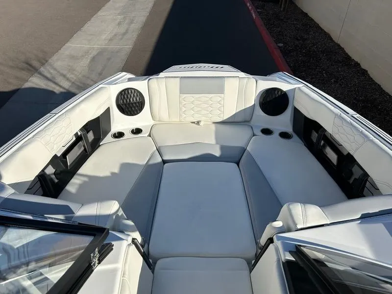 Slide: The Image of 2025 Malibu 24 MXZ boat interior with white seating and cup holders. - 14