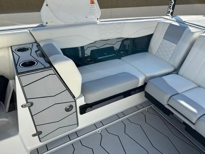 Slide: The Image of 2025 Malibu 24 MXZ boat interior with sleek seating and cup holders. - 16