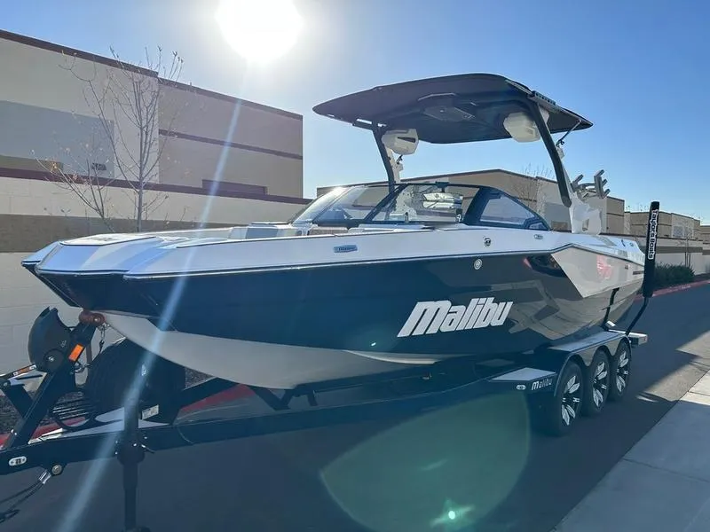 Slide: The Image of 2025 Malibu 24 MXZ boat on trailer under bright sunlight. - 3