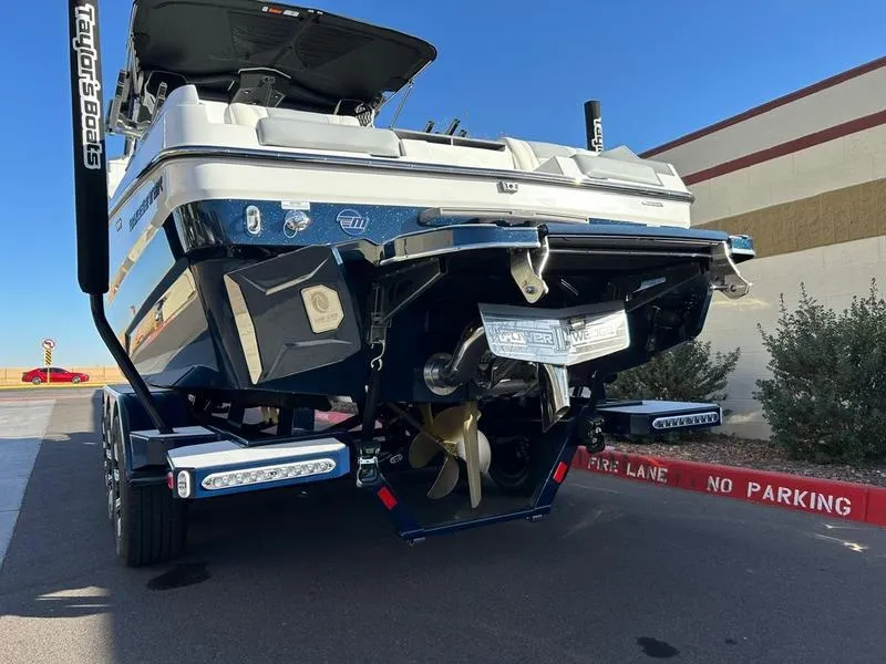 Slide: The Image of 2025 Malibu 24 MXZ boat rear view, parked on a trailer in a no parking zone. - 4