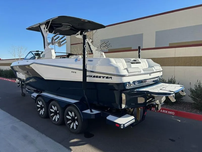 Slide: The Image of 2025 Malibu 24 MXZ boat on trailer, parked outdoors, showcasing sleek design and modern features. - 5
