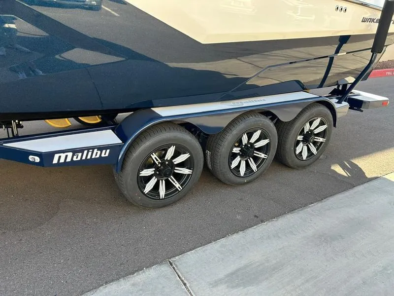 Slide: The Image of 2025 Malibu 24 MXZ boat trailer with triple axle and sleek black wheels. - 6