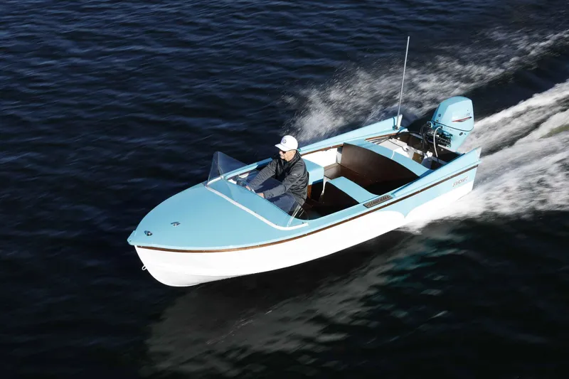 Slide: The Image of 2025 Starcraft 57 SKI CHAMP boat cruising on water, featuring sleek blue and white design. - 1