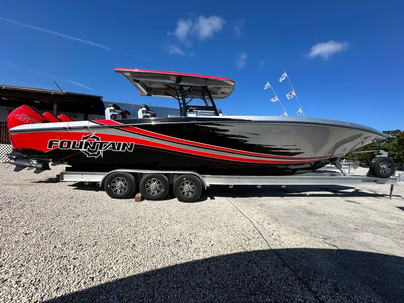 Slide: The Image of 2021 Fountain 38SC boat on trailer, sleek design, black and red accents, clear blue sky. - 1